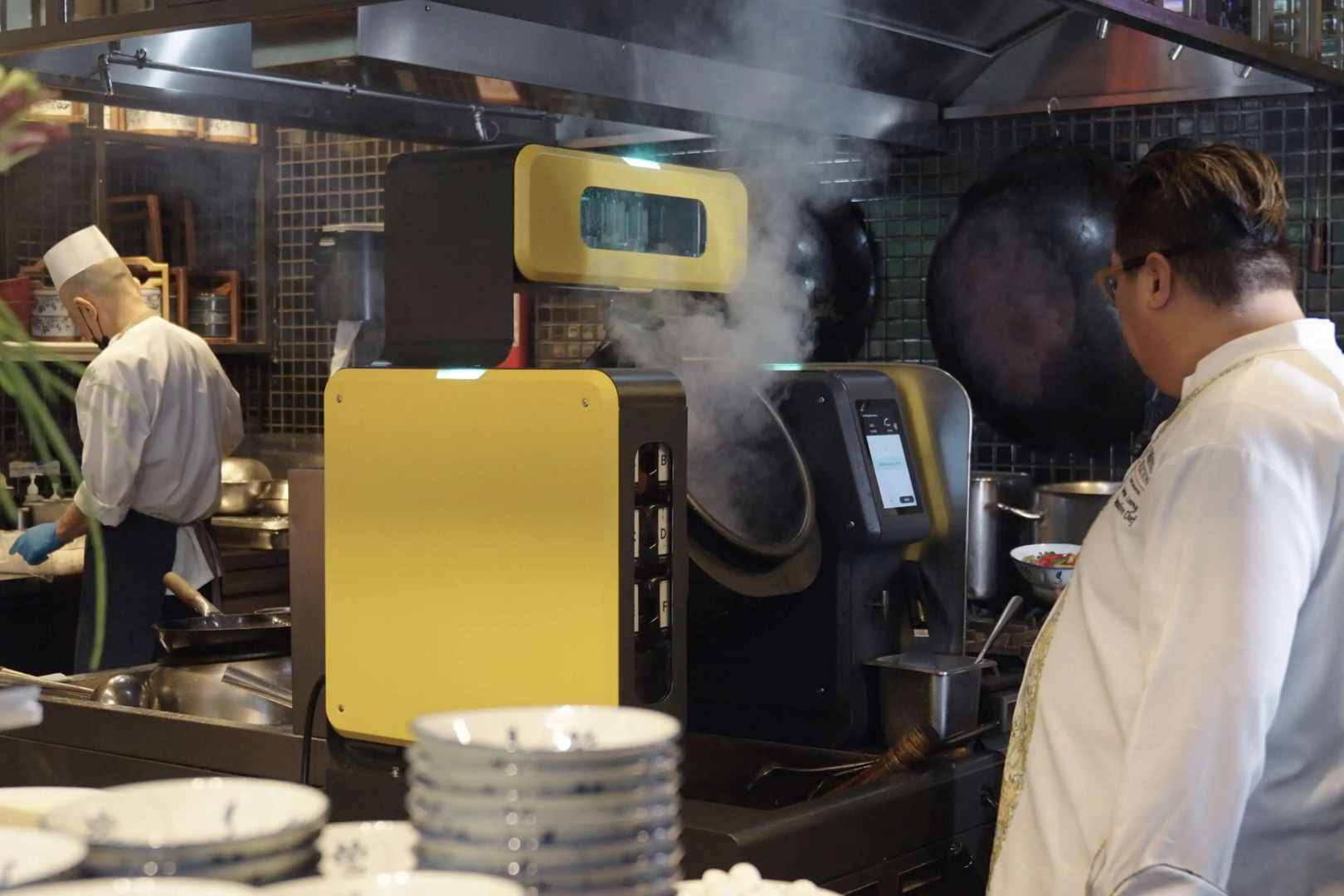 BotInKit Omni cooking in a restaurant kitchen beside a chef