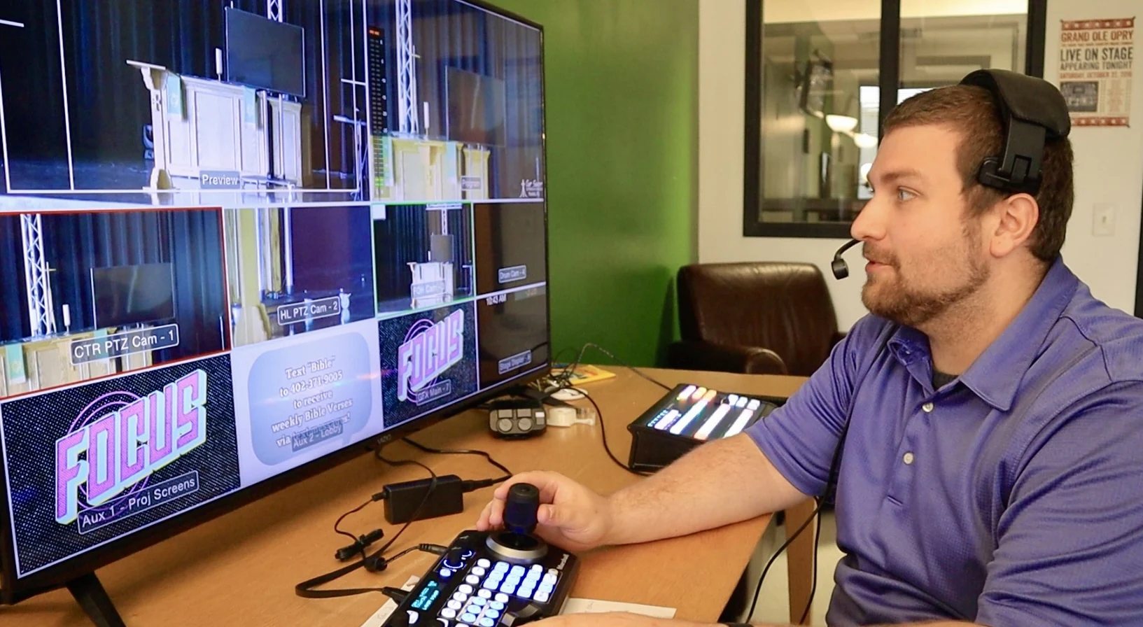 Volunteer in a headset operates a camera console at a multi-camera livestream desk.