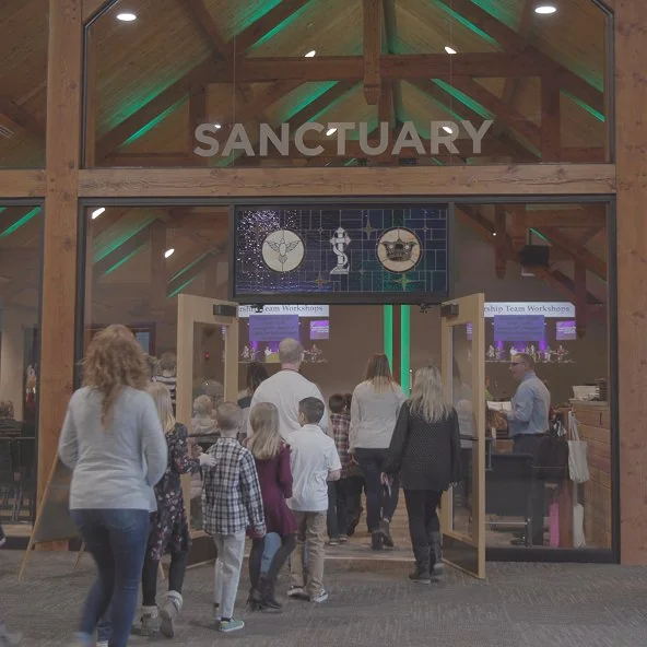 Worshippers walk through the doors marked Sanctuary into the timber-framed worship space.