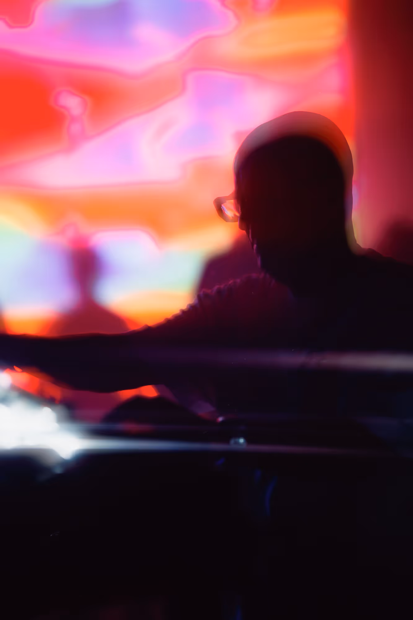 Silhouetted person with glasses against a vibrant, colorful abstract light background.