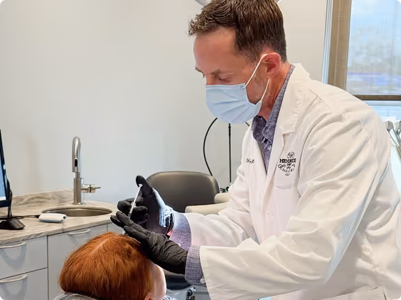 Doctor wearing mask and gloves examining patient's eye in a clinical setting.