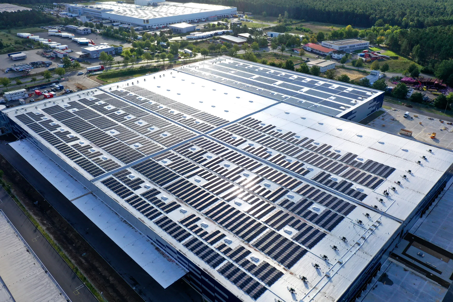 Großes Flachdach mit zahlreichen ESG Solarmodulen auf einem Industriegebäude in einer Gewerbezone.