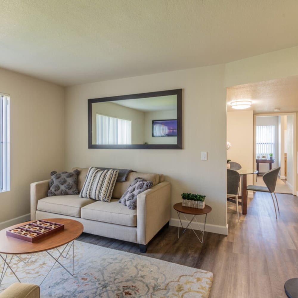 Living area with sofa, coffee table, wall mirror, and view of dining area