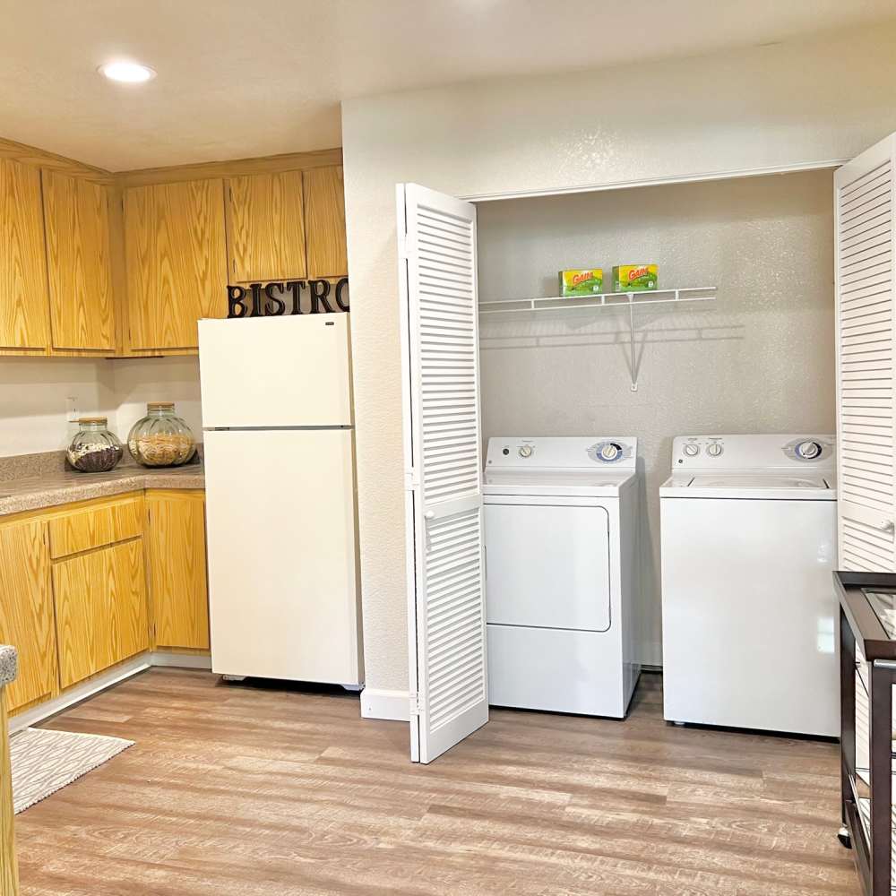 Kitchen with brown cabinets and view of laundry room wth white appliances