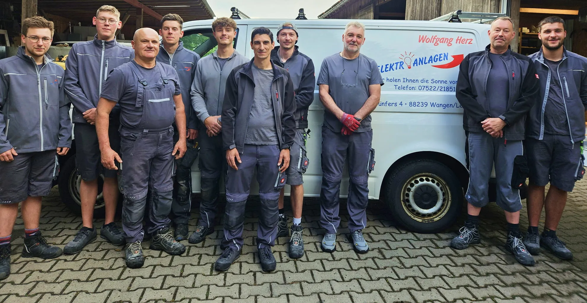 Montageteam von Elektroanlagen Herz vor einem Servicefahrzeug.
