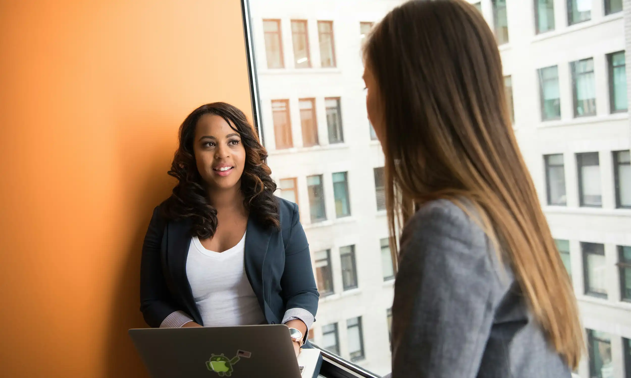 Two professionals in conversation beside an office window