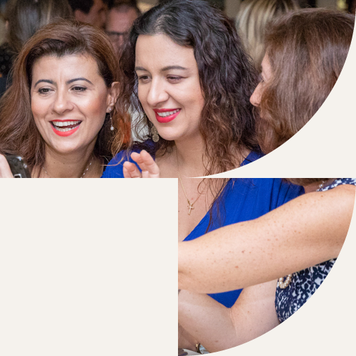 IPG members smiling as they look at a phone together during a conference evening
