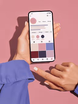 Person holding smartphone showing a color palette app against a pink background.