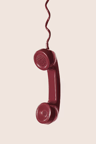 Vintage maroon telephone handset hanging with a coiled cord on a beige background.