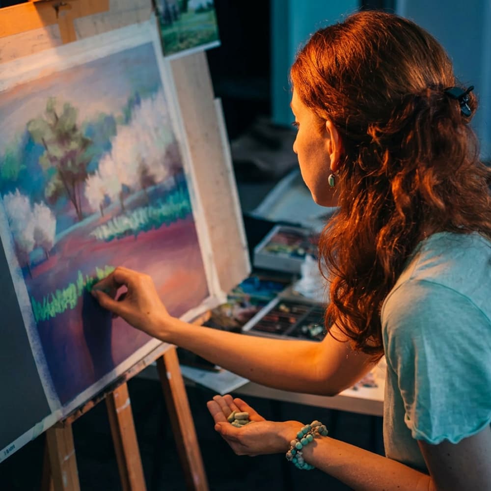 A painter working at an easel on a landscape in soft pastel