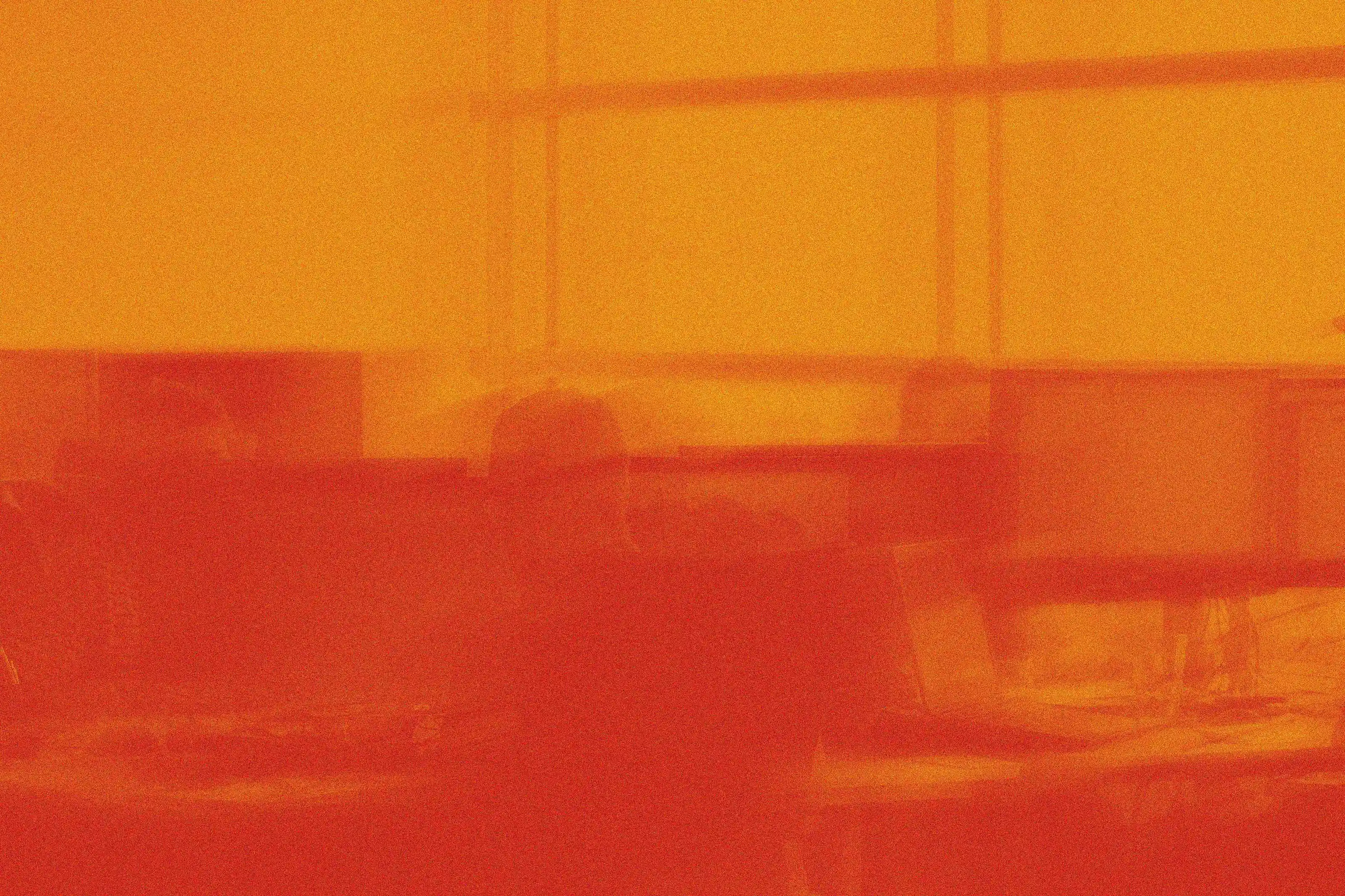 Office scene with desks, computer monitors, and laptops, tinted with an orange-red gradient filter.