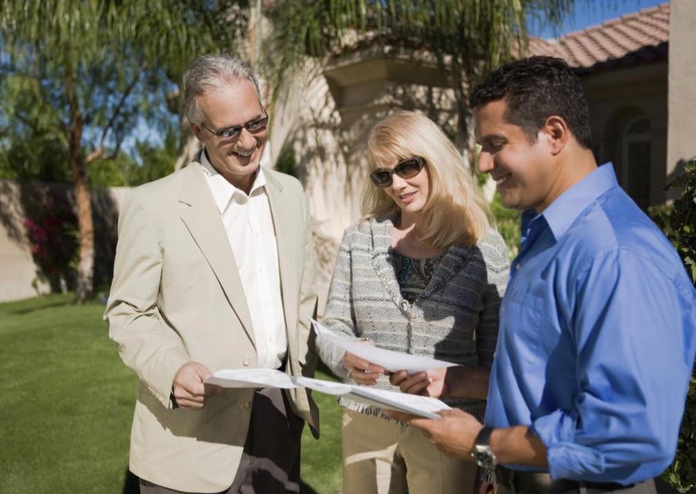 A realtor meeting with two clients outside of a new potential property.