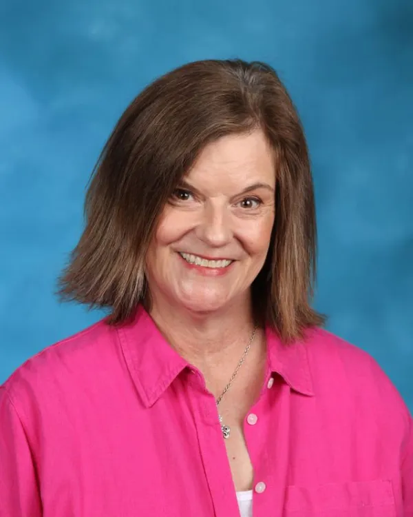 Staff portrait of Liz Bailey smiling in pink shirt