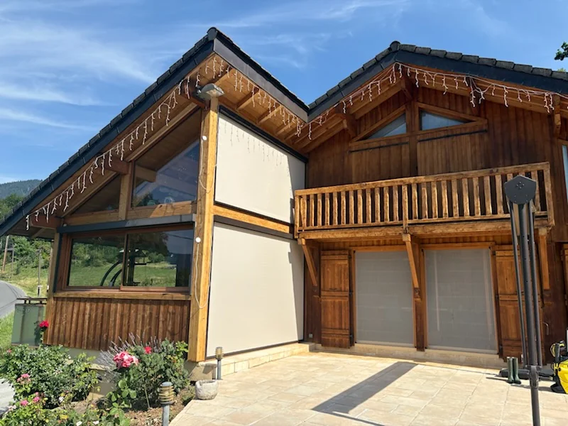 Store screens verticaux déployés sur la véranda d'un chalet à Viuz-en-Sallaz