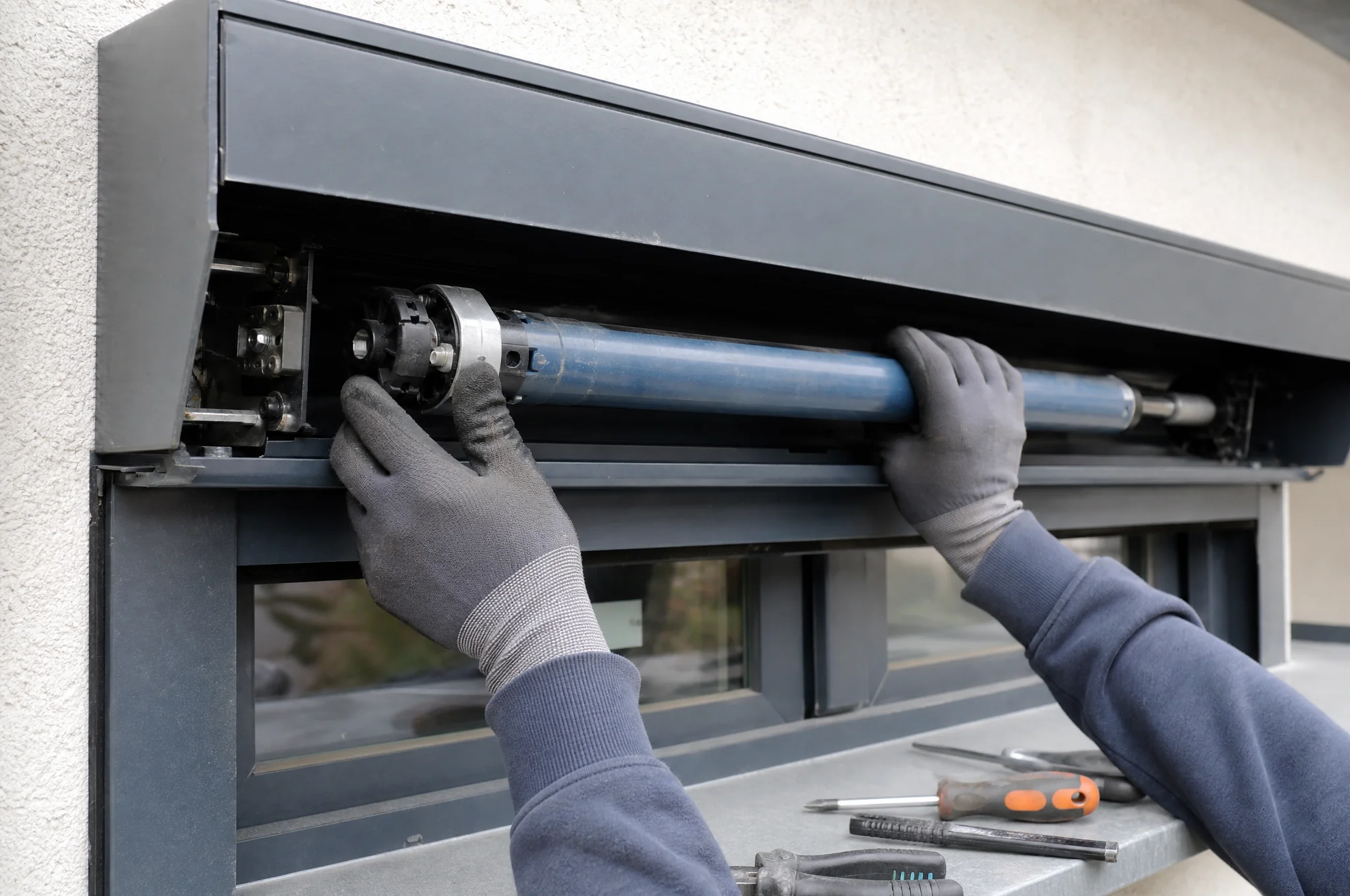 Technicien installant un moteur tubulaire dans le coffre d'un volet roulant aluminium