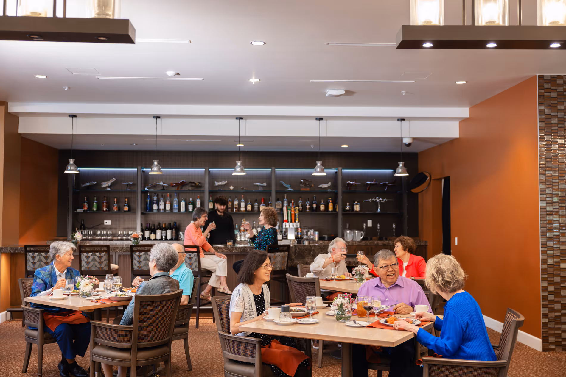Group of elderly people enjoying meals and drinks together in a cozy restaurant dining area.