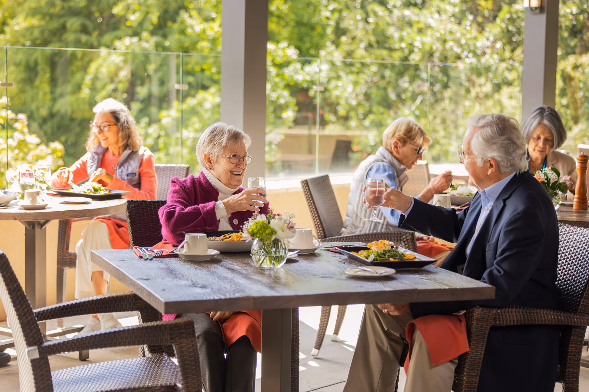 Elderly couple enjoying a meal and drinks together at an outdoor restaurant table.