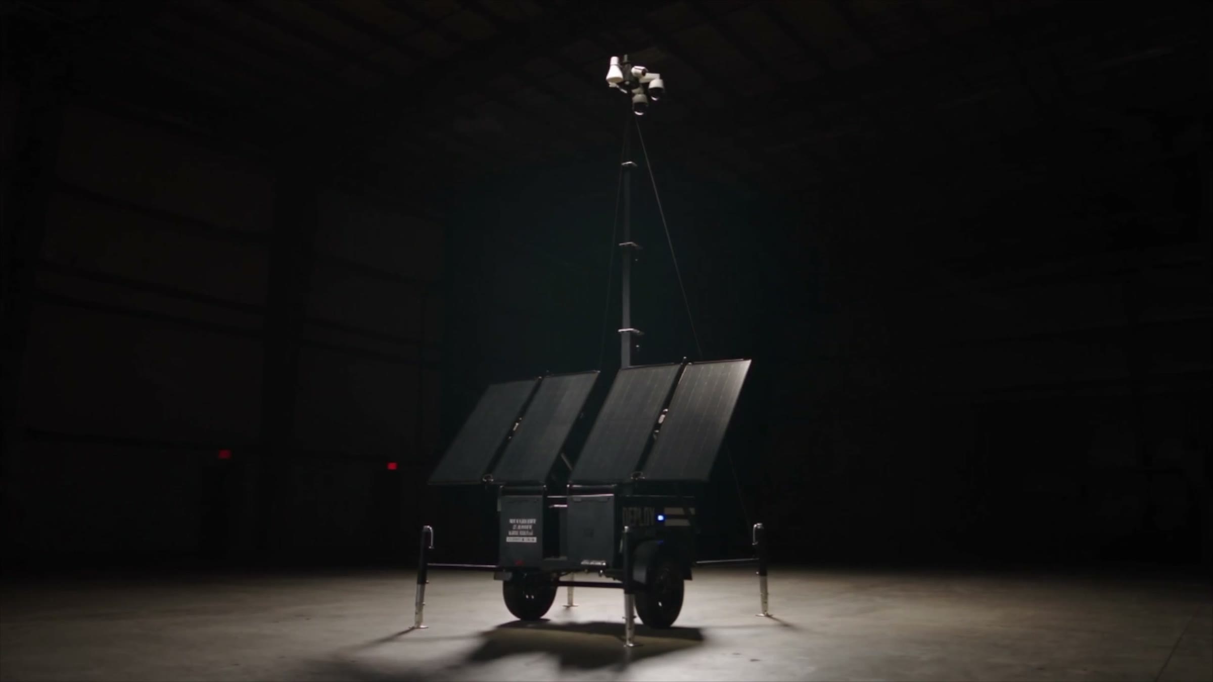 The Deploy Surveillance unit in a dark warehouse, mast raised, lit from above.