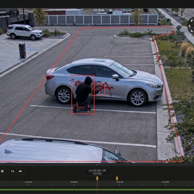 A camera view of a person vandalizing a parked car.