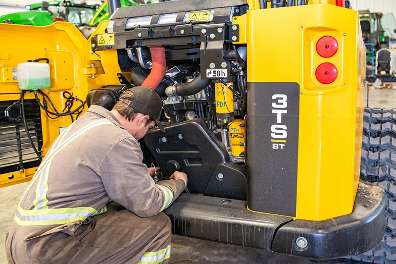 Technician prepares a 3TS 8T loader for Delta, BC August heat; labels read “50 h” and “COLD FILL.”
