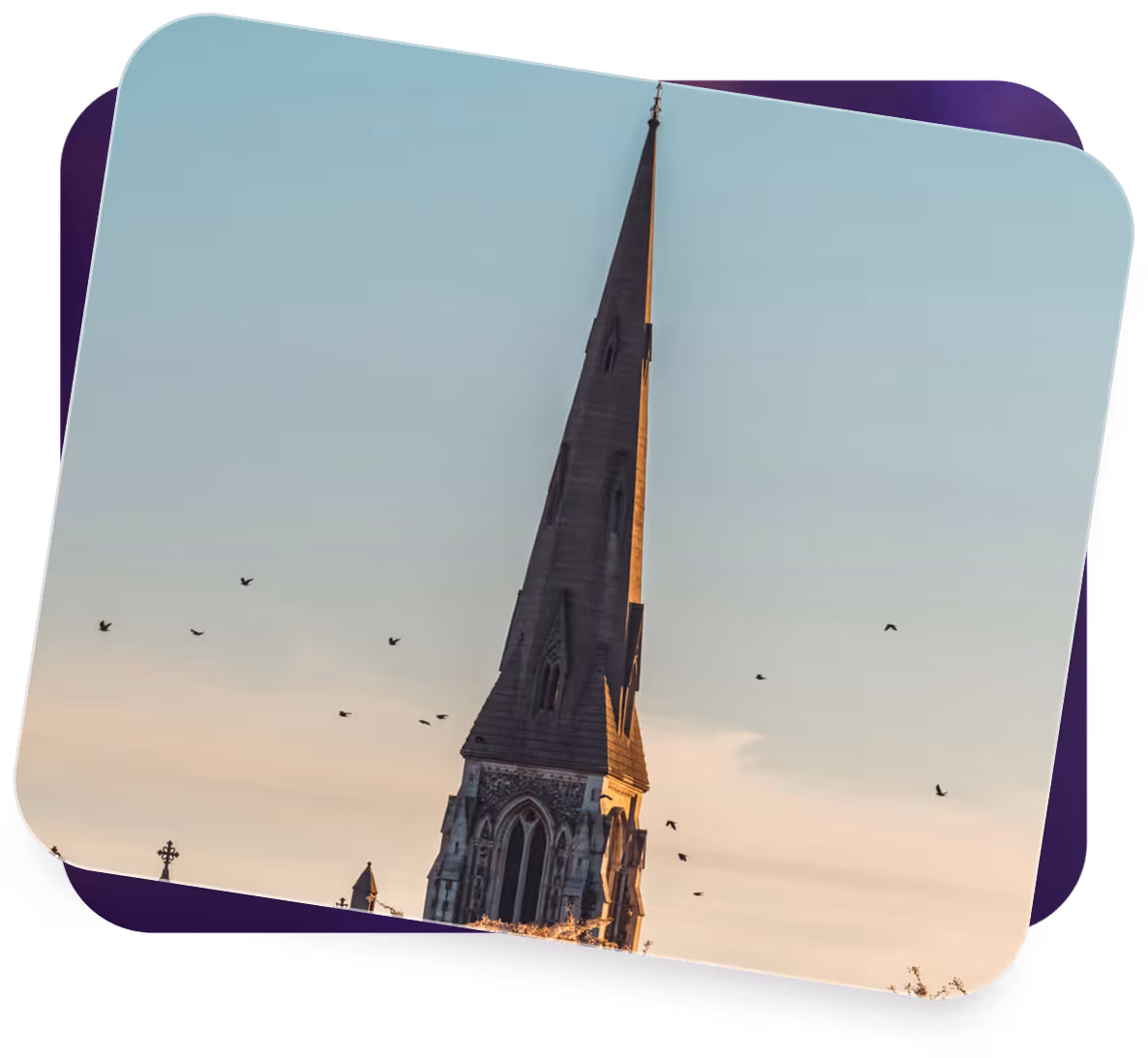 Tall church steeple with arched windows against a blue sky and birds flying nearby.