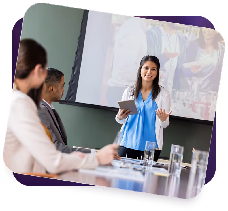 Woman presenting with tablet to colleagues seated at conference table with glasses of water.