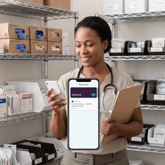 Healthcare worker smiling while using phone showing KleerCard purchase notification for $112.75.