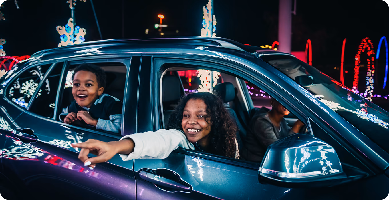 Two guests pointing at the light displays from inside their car
