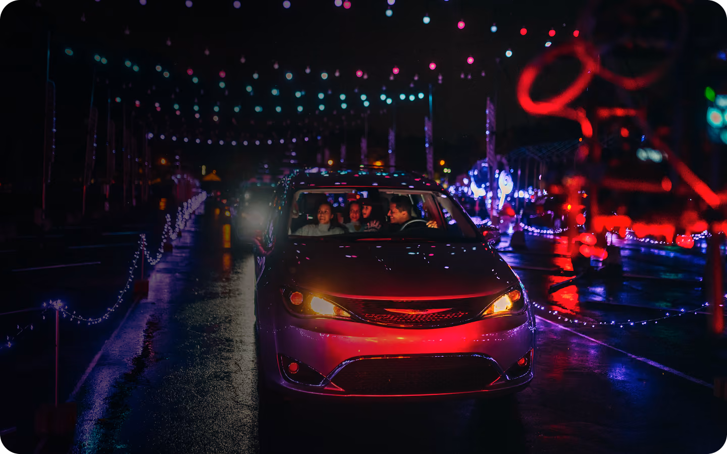Cars driving through red and blue light displays on a wet evening
