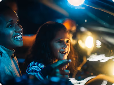 Two friends smiling in the front seats as the lights pass by