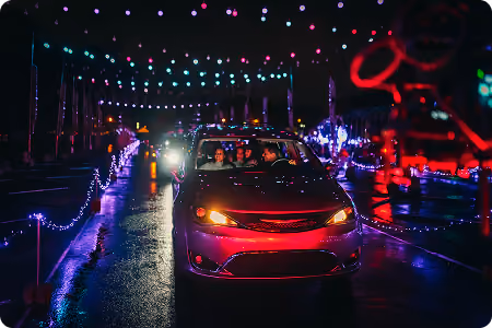 Cars driving past red and pink light displays
