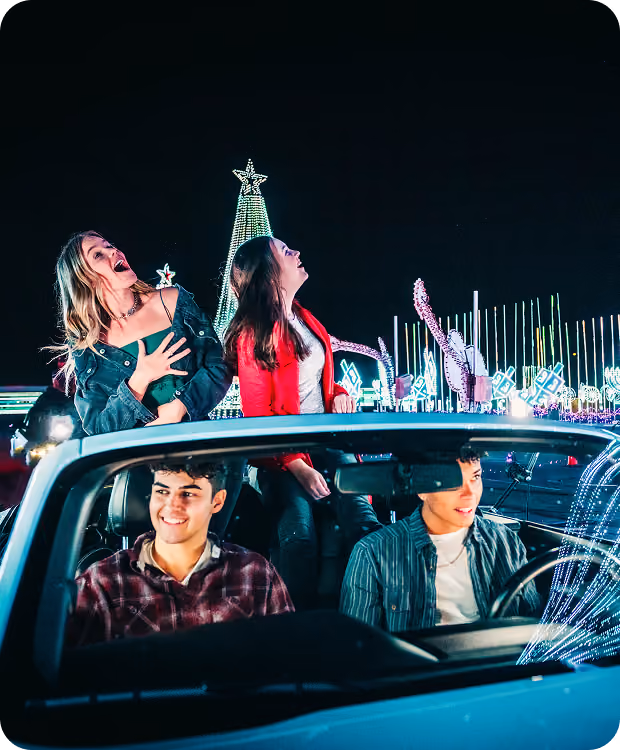 Guests standing through the sunroof of their car among the light displays