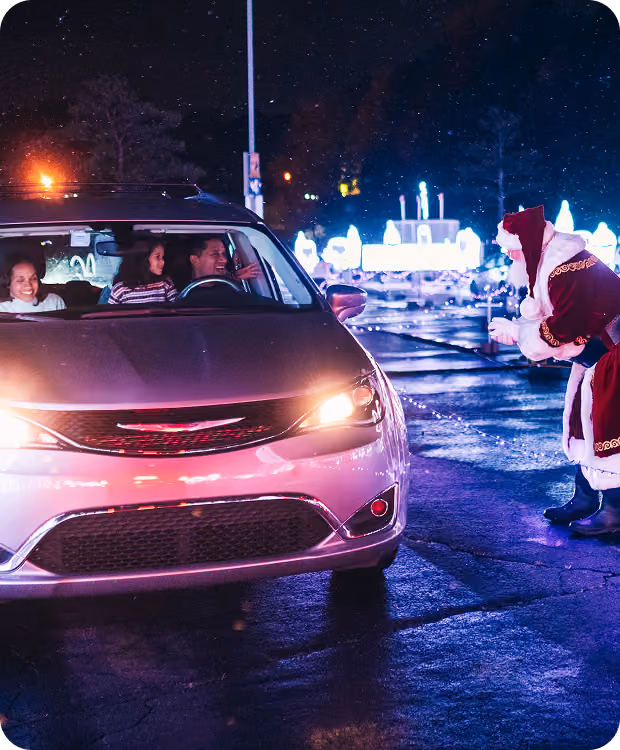 Santa greeting a family in their car at the entrance to the light show