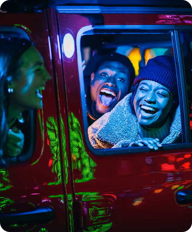 Three guests laughing together in their car at the drive-through show