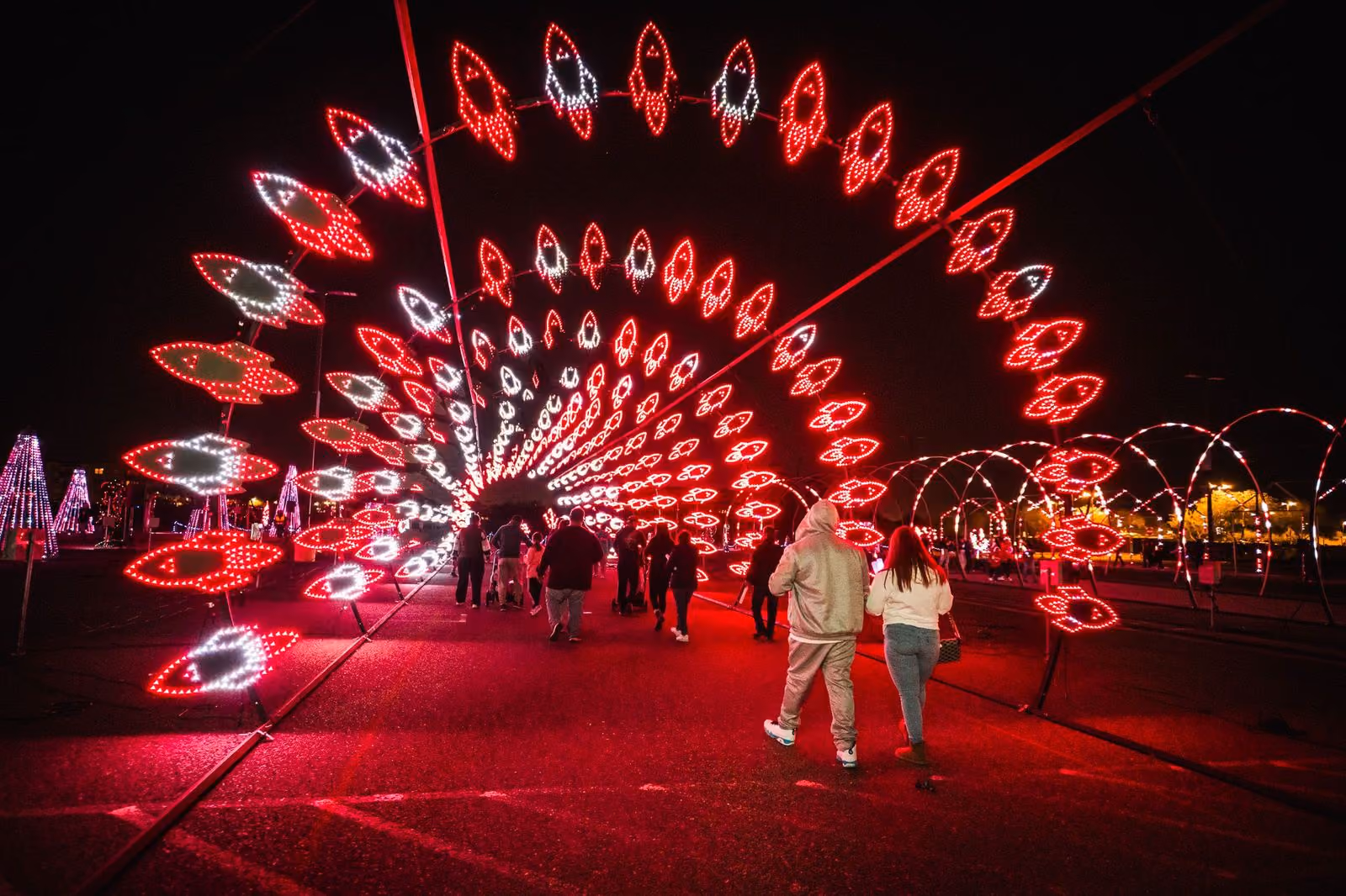 Guests walking past a giant red peacock light display at a group event