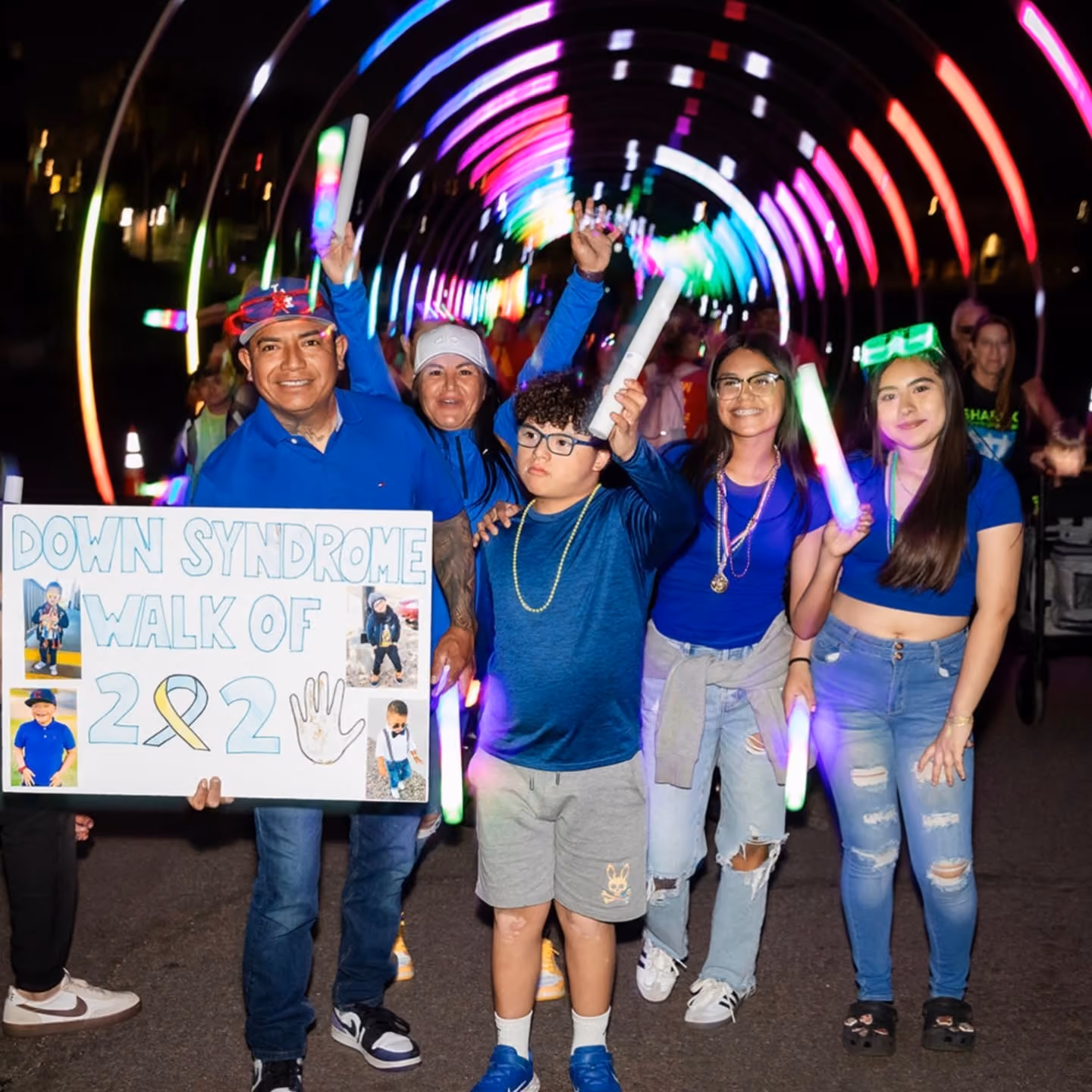 Family holding a Down Syndrome Walk 2022 sign with glow sticks at the light show