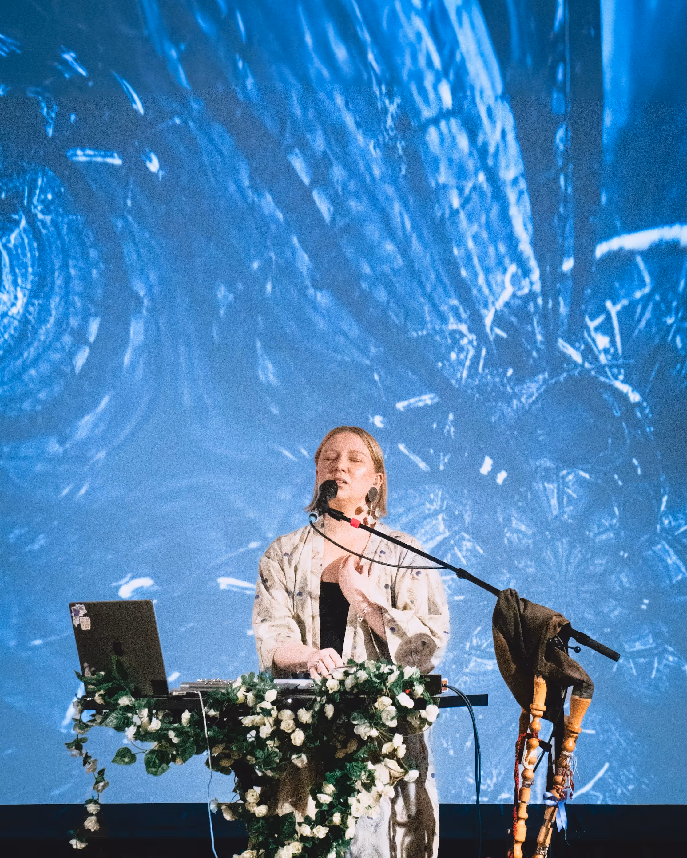 Susanna Viktoria performing live with electronic setup and floral stage decorations