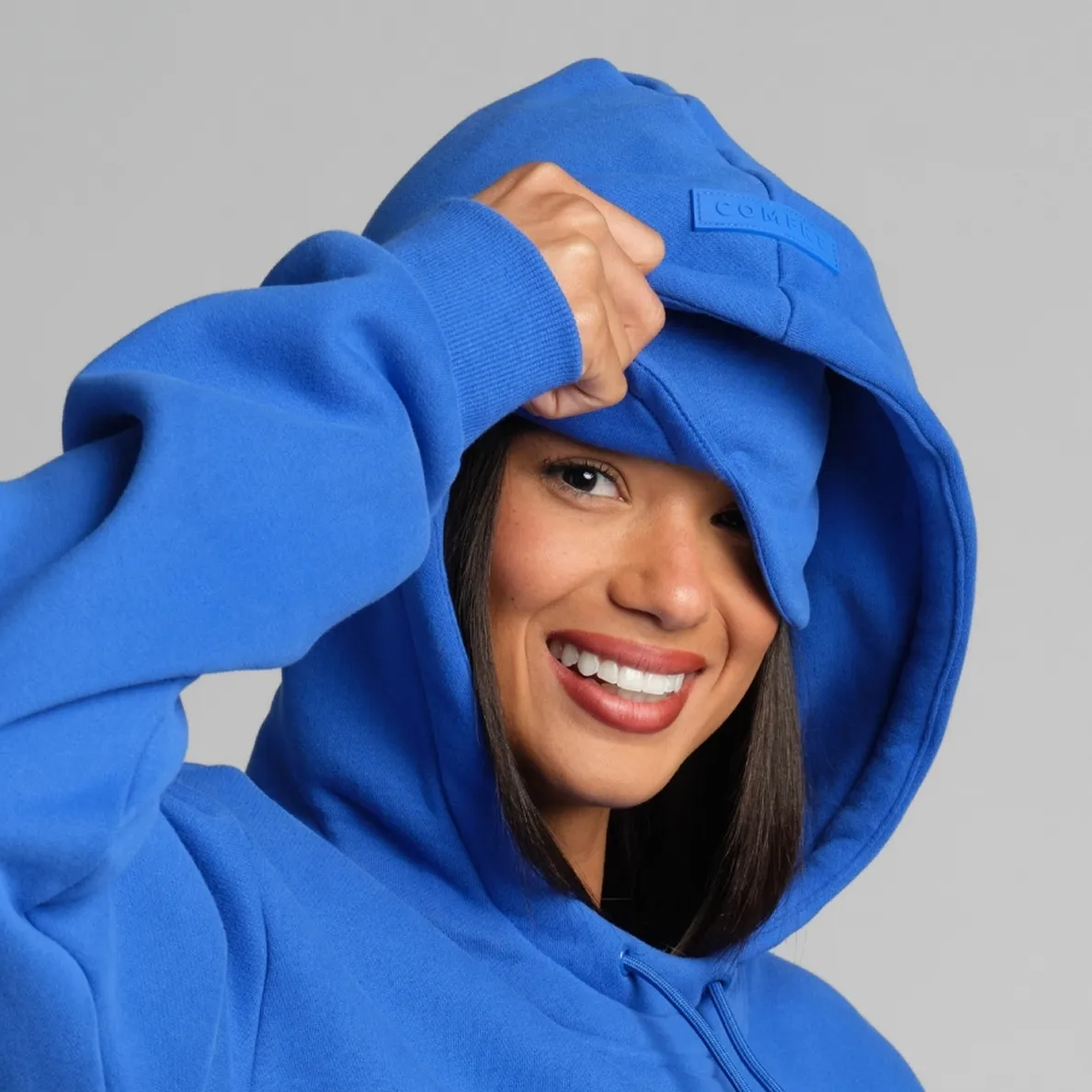 Woman pulling the oversized double-lined hood of a blue Airplane Mode Hoodie over her head