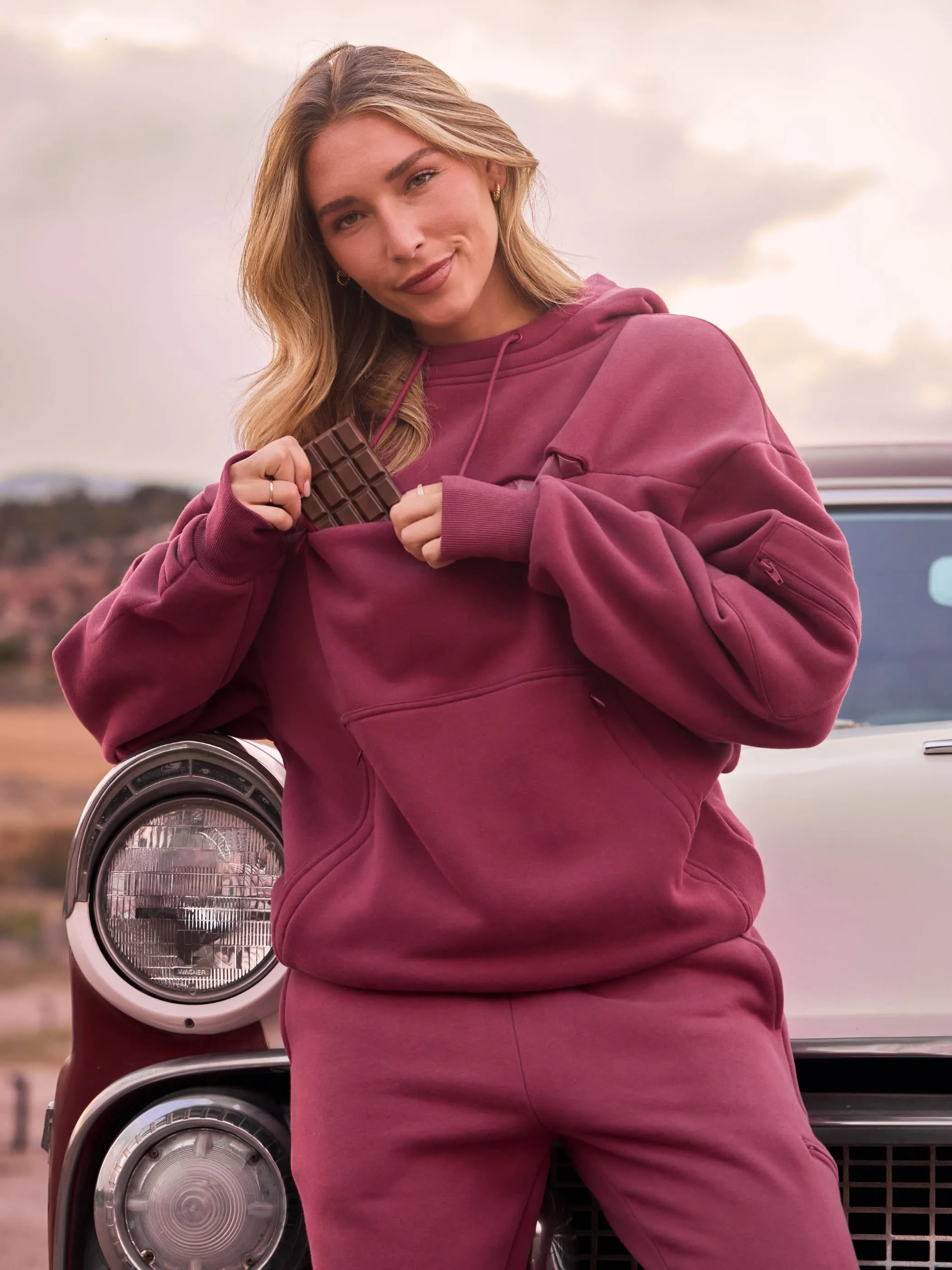 Woman wearing a Berry Snak Hoodie with snacks in the chest pocket