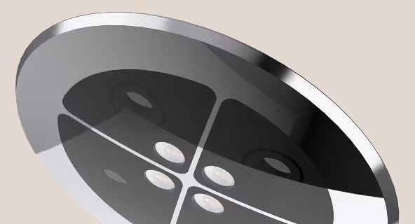 Close-up of a shiny metallic four-hole button on a beige background.
