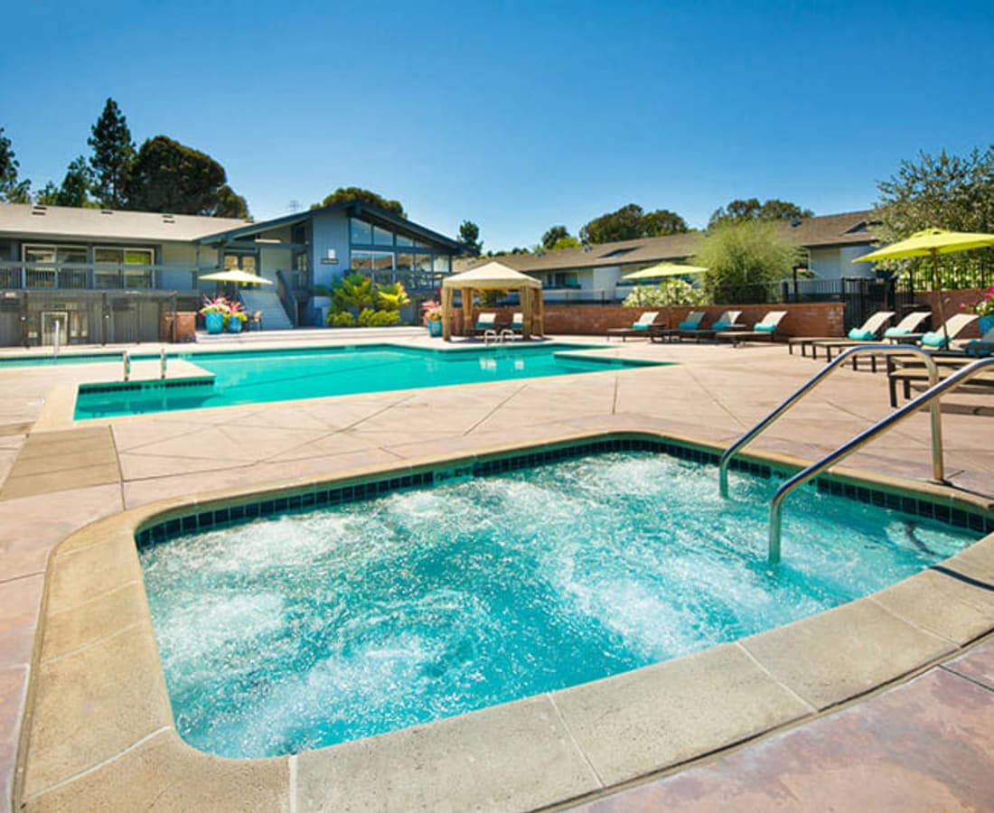 Swimming pool and spa with lounge chairs and umbrellas