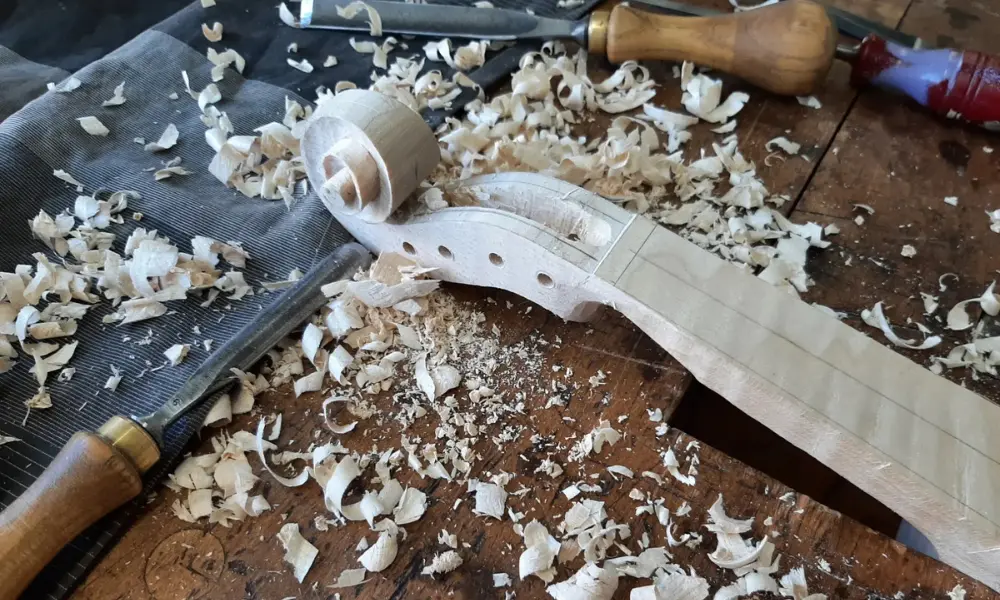 Geigenbauer schnitzt die Schnecke einer Violine, Holzspäne auf der Werkbank