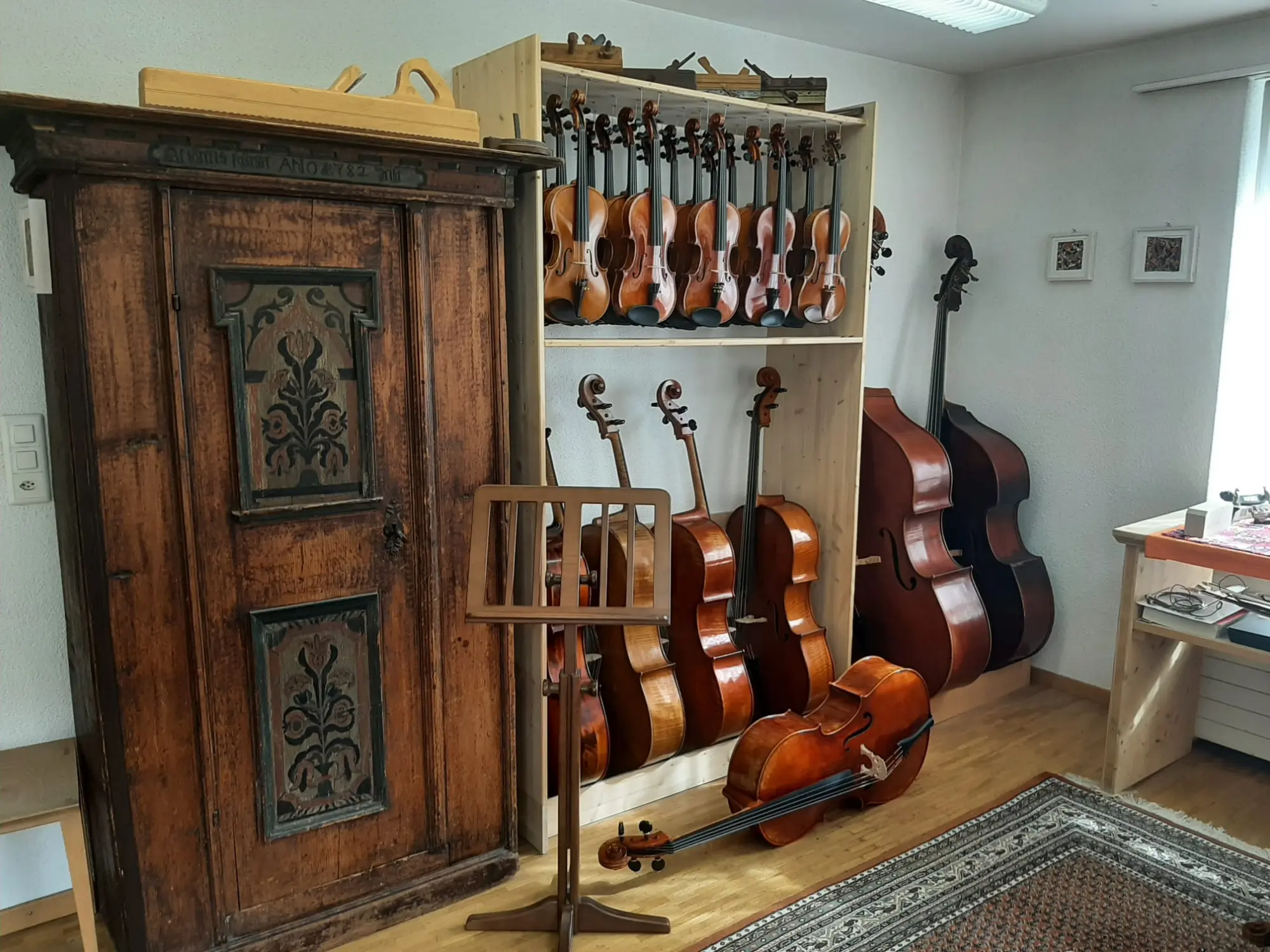 Verkaufsraum mit Bauernschrank, Celli, Kontrabässen und Violinen
