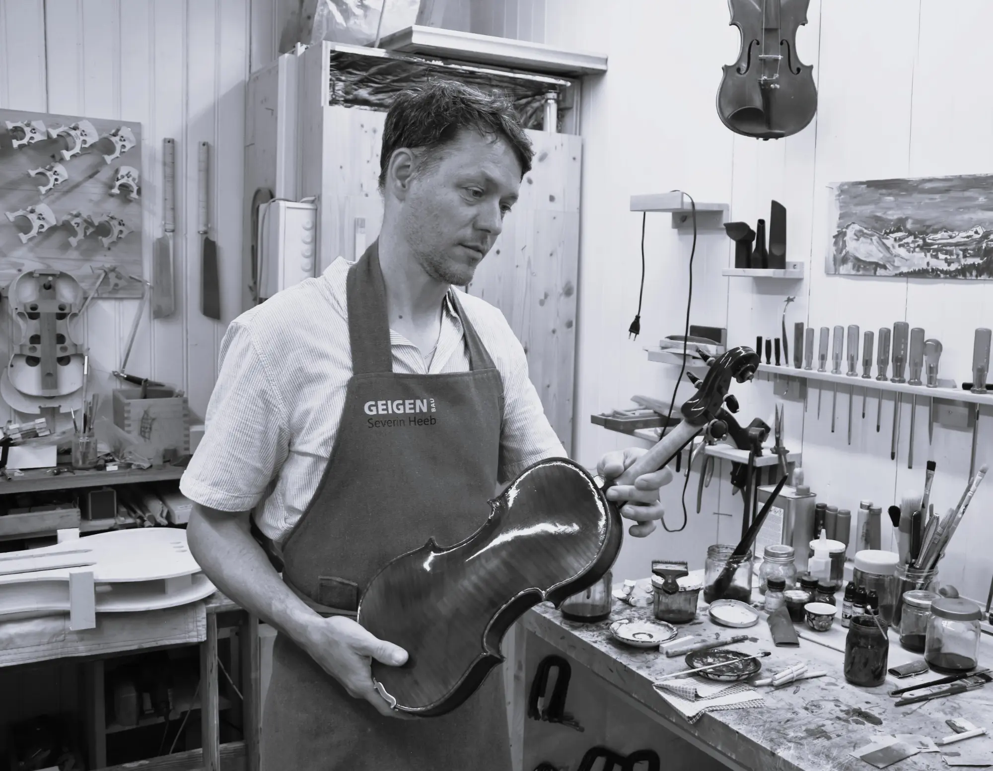 Geigenbauer stimmt ein Cello im Atelier