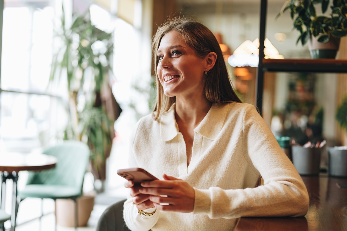 Profissional de marketing sorrindo com celular na mão