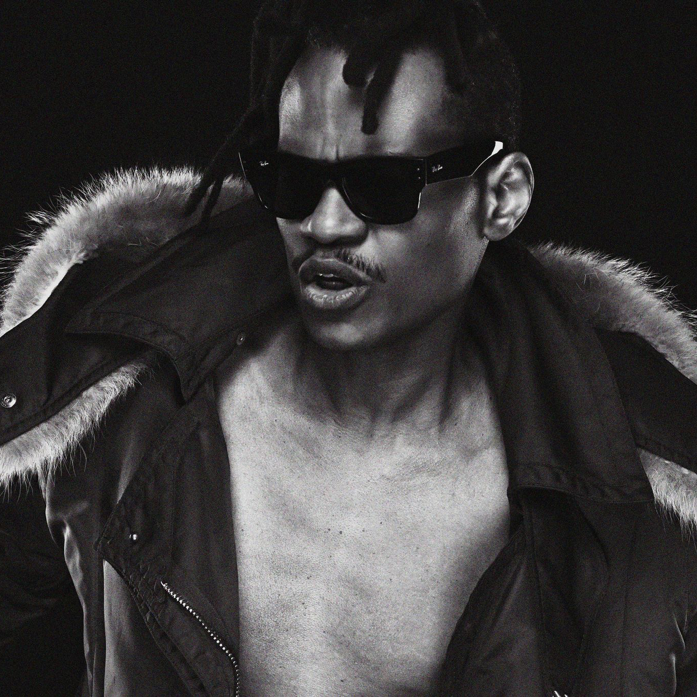 The Mighty Cobra in sunglasses and a fur-collared jacket, black-and-white studio portrait.