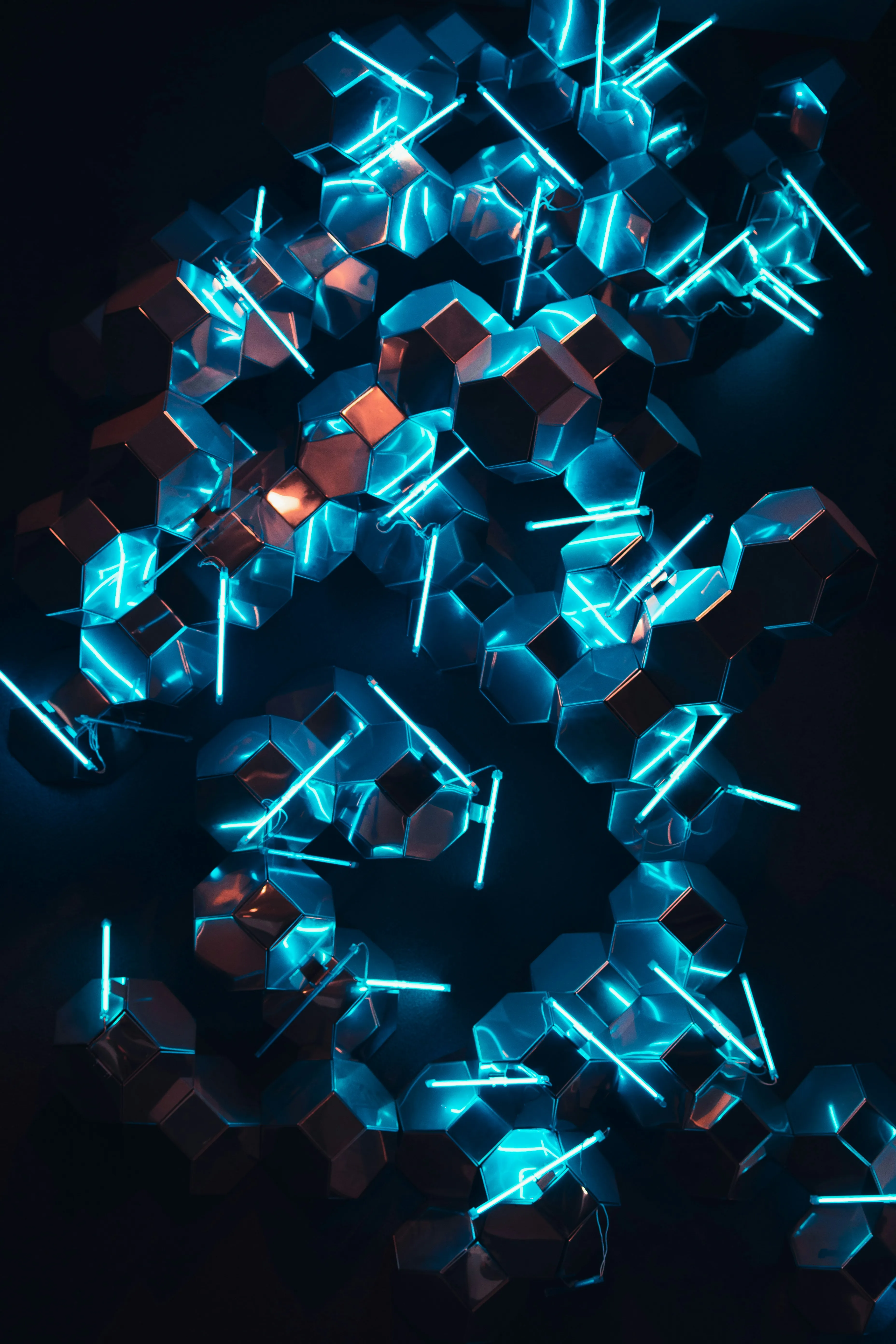 Cluster of metallic hexagonal shapes with bright blue neon light rods on a dark background.