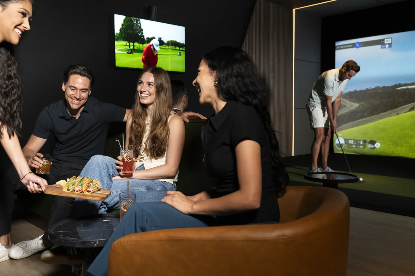 Five friends laughing over tacos in a bay at The Tips Golf