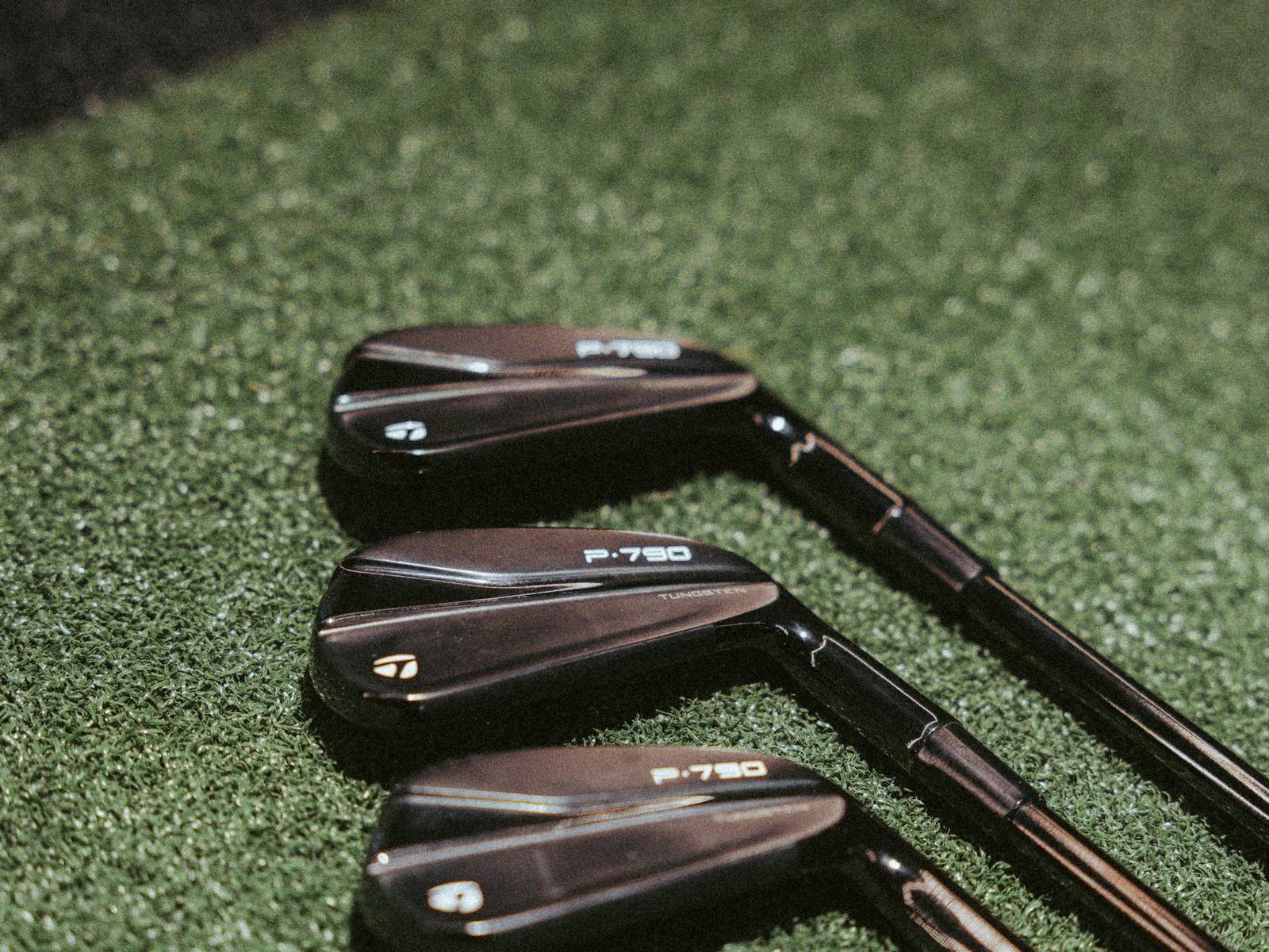 Three irons resting on the hitting turf at The Tips Golf.