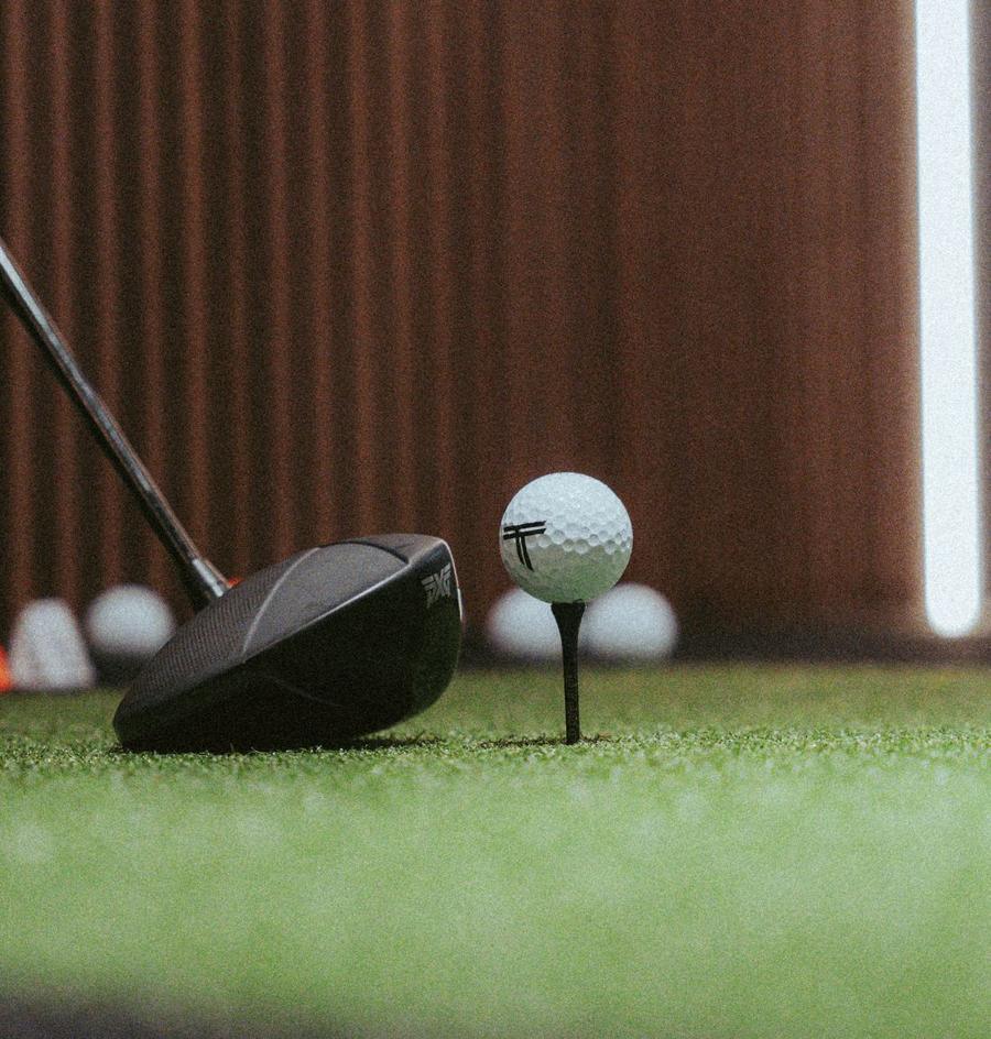 A driver lined up behind a teed ball with The Tips logo.